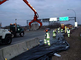 Highway workers in reflective gear building a dike on I-35 in Burnsville