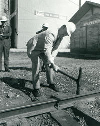Man in suit pounding rail spike
