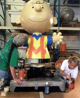 2 women painting Charlie Brown statue
