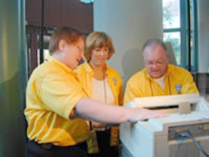 2 women, man fixing printer