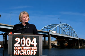 Woman at lectern in front of bridge