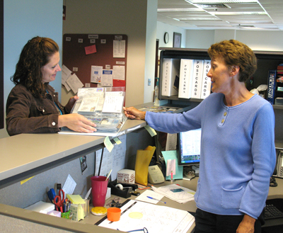 Cindy Syria (at right) checks some recent postcard entries with Jessica Leslie, Human Resources. Photo by John Bray 