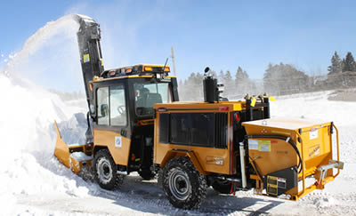 Trackless machine clearing snow