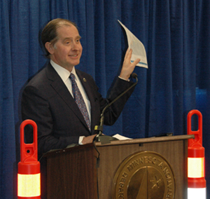 Commissioner Charlie Zelle waving funding chart at news conference