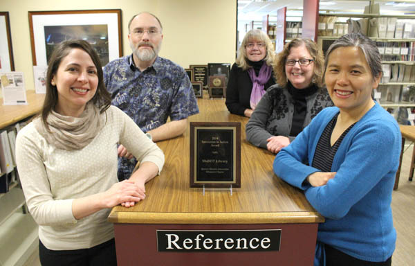 4 women, 1 man standing in library by award