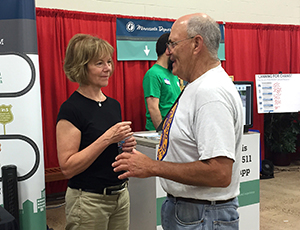 Photo of Tina Smith talking to a visitor at the MnDOT State Fair booth. 