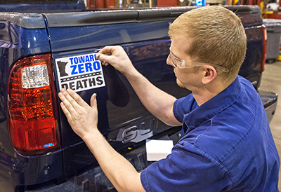 Photo of Joe Musolf attaching a TZD decal to a vehicle.