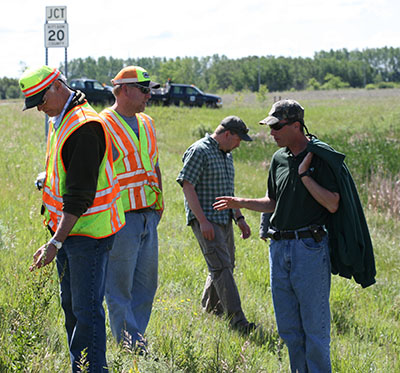 Four men in a roadside ditch full of noxious weeds