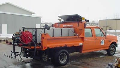 Orange MnDOT truck with silver tank in its bed, parked at truck station