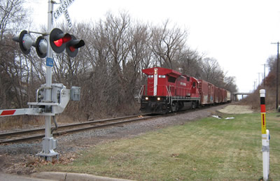 Red train approaching highway intersection