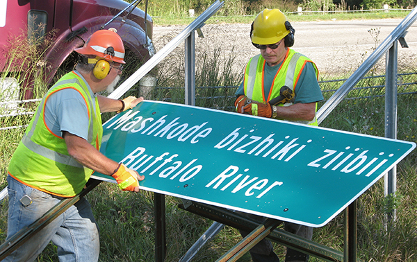 Photo of District 4 sign crew putting up dual language sign.
