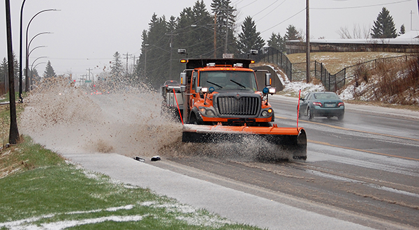 Orange snowplow pushes slushy mixture from road