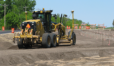 Road grader smooths out dirt in construction zone